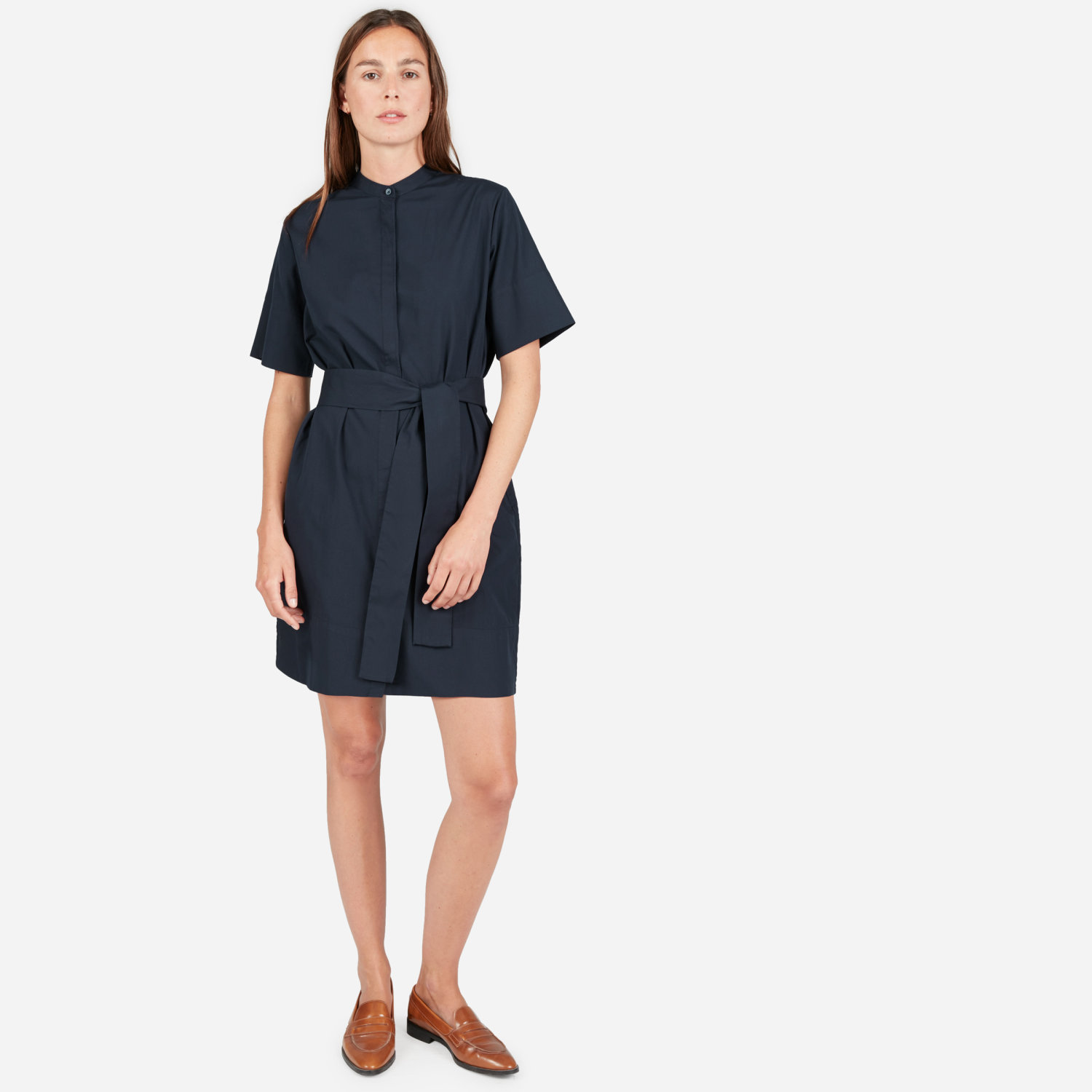 Dark navy collarless, above-the-knee-length dress with wide fabric belt tied at the waist in matching fabric.