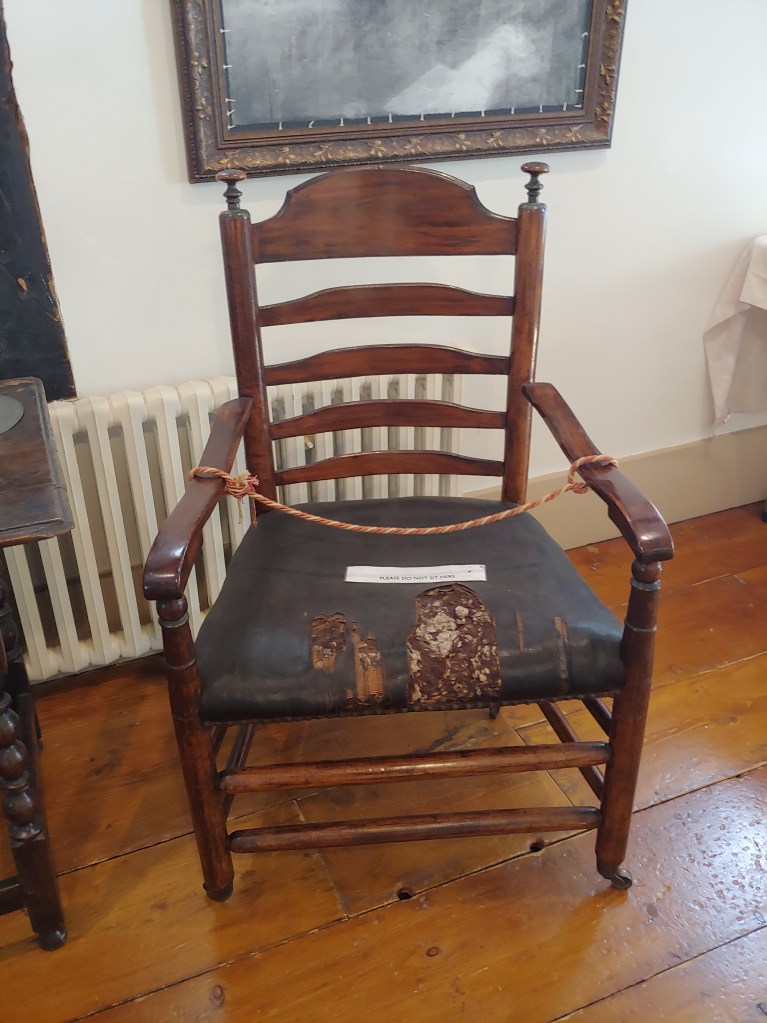 An old wooden chair with a worn leather seat.