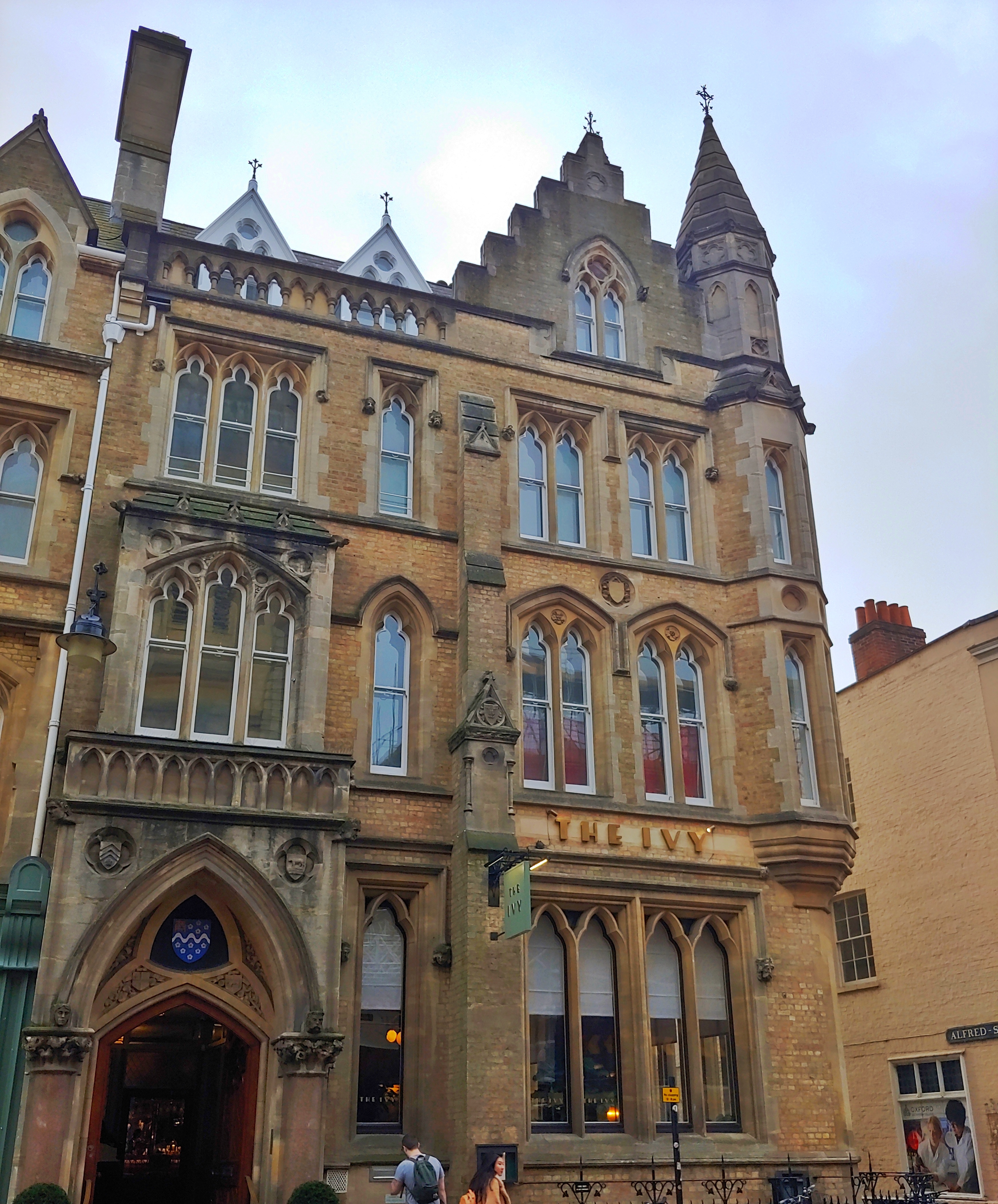 Photo of a three story neo-Gothic building on Oxford High Street, with 'The Ivy' written over the window in art deco lettering