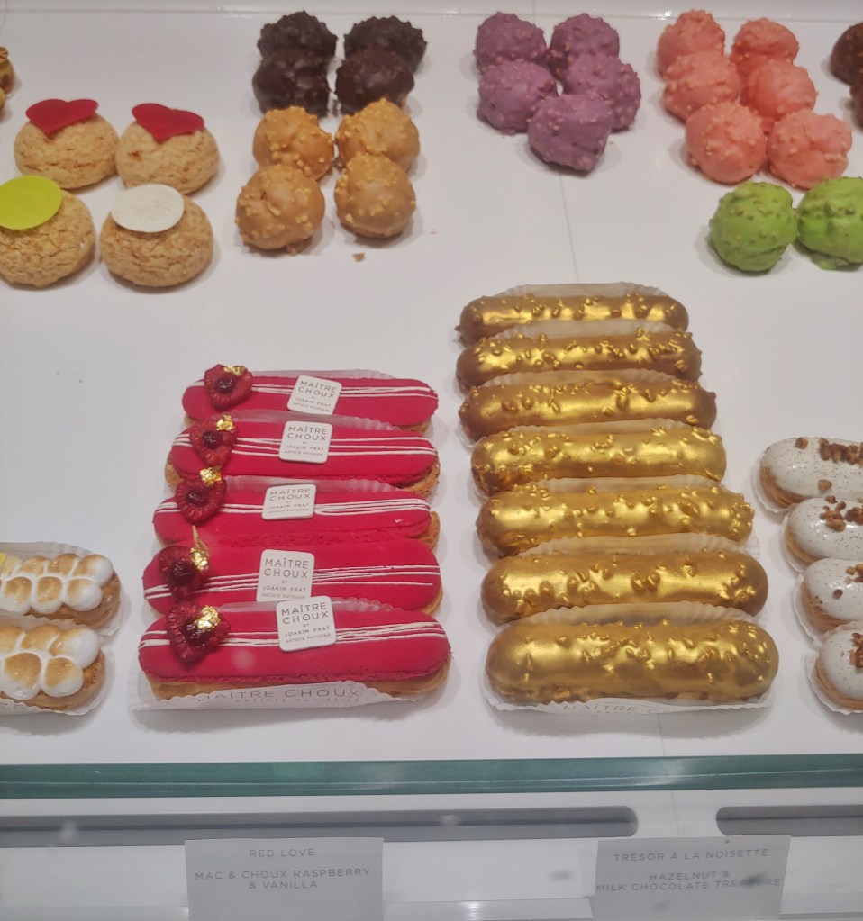 Photograph of the Maître Choux shop window with various colour choux buns and pastries.