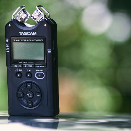Close up image of a Tascam sound recording device with a green, leafy background