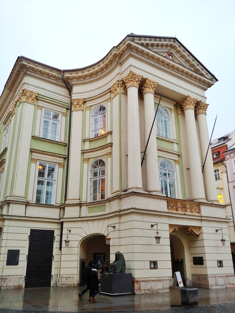 The Estates Theatre, Prage, with Neoclassical architecture, green walls, and cream columns with gold capitals.