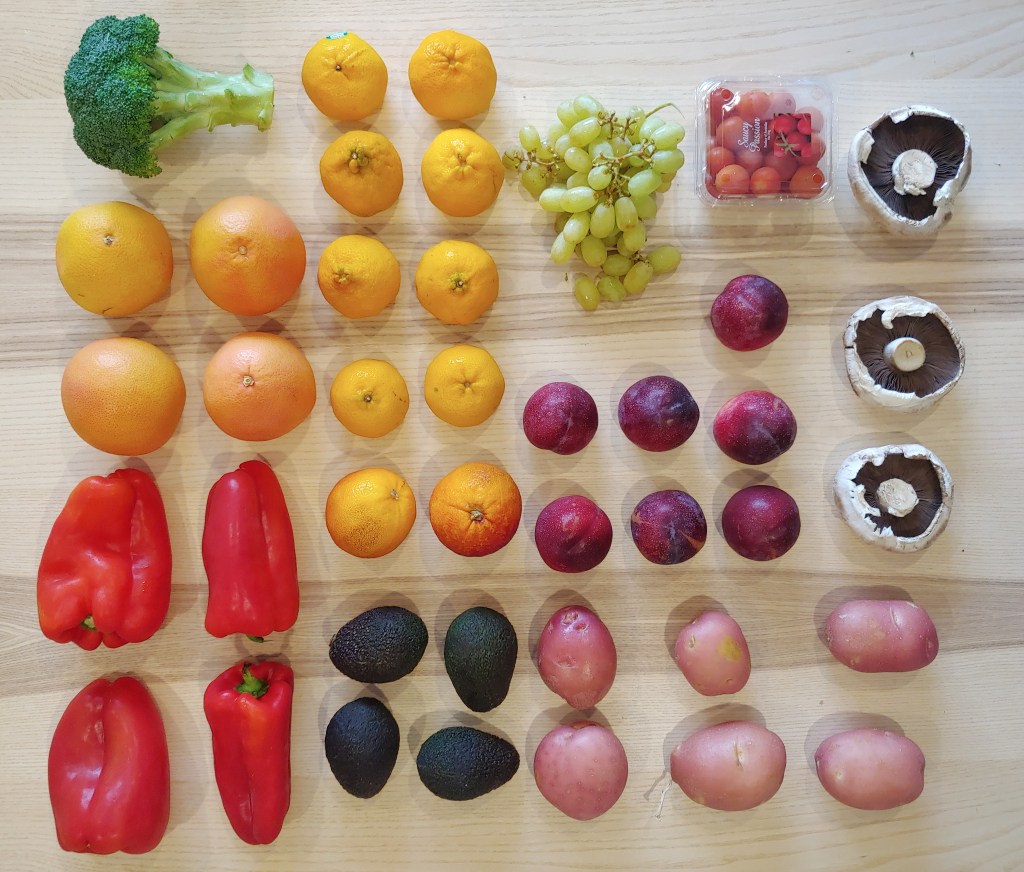 Fruit and vegetables arranged on a grid on a wooden table.