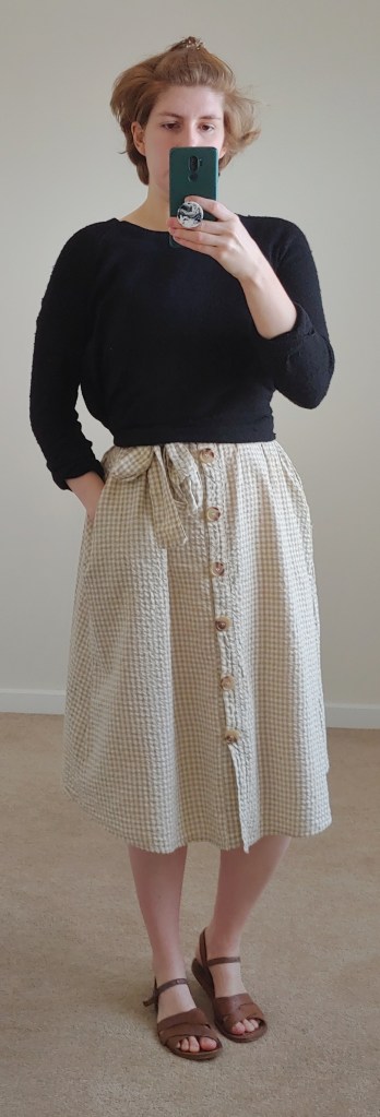 Full length photo of gingham dress with black jumper tied over it.