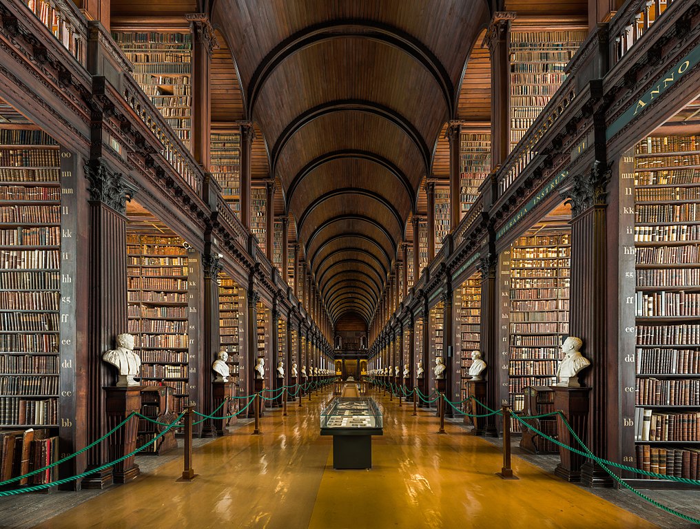 Image of the Long Room at Trinity College Dublin's Old Library, showing a barrel-vaulted ceiling and tall bookshelves on either side stretching into the distance.