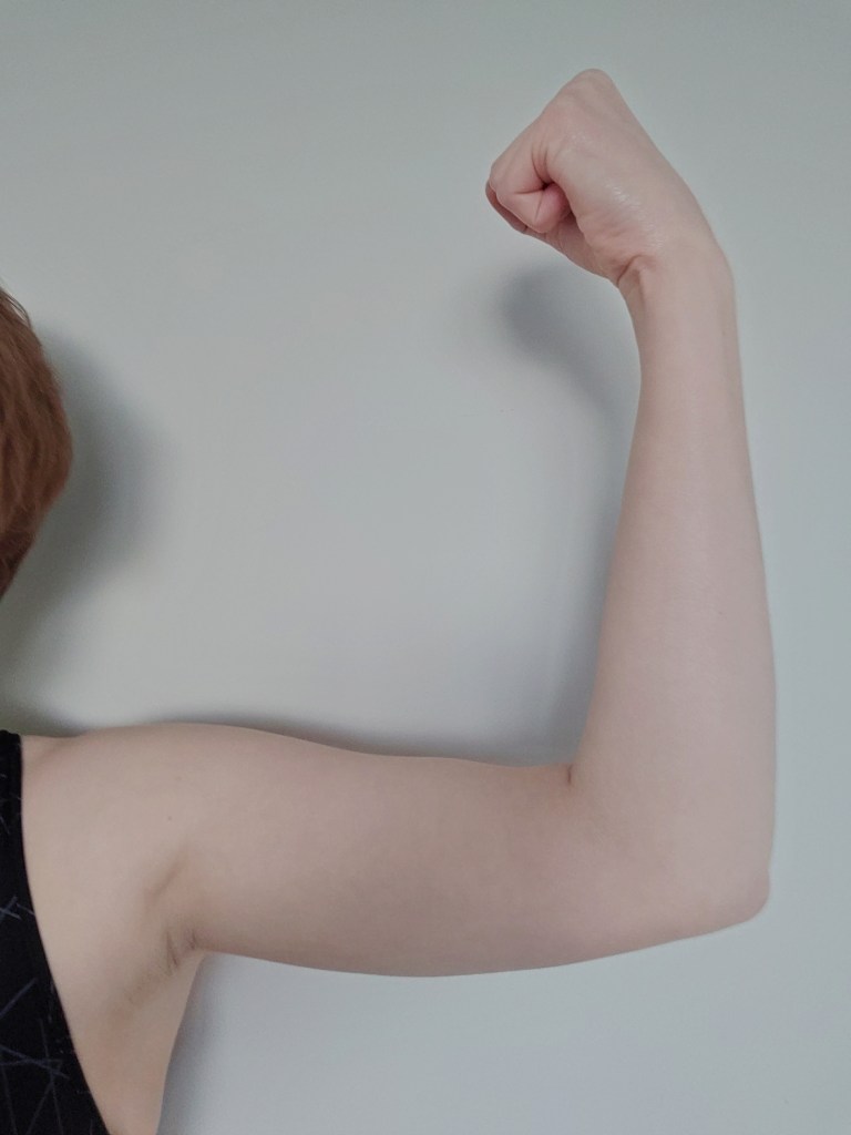 Arm tensed and held parallel to wall showing muscle definition.