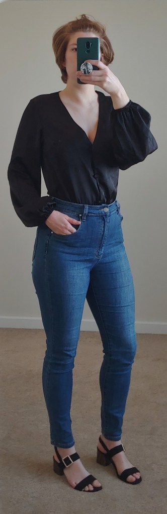 Full length photo wearing jeans, black block sandals and a black long-sleeved one-piece from Missguided.