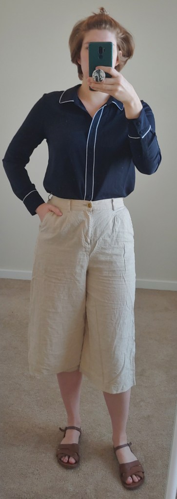 Full length photo wearing cream culottes, a navy and white piped shirt, and brown sandals.