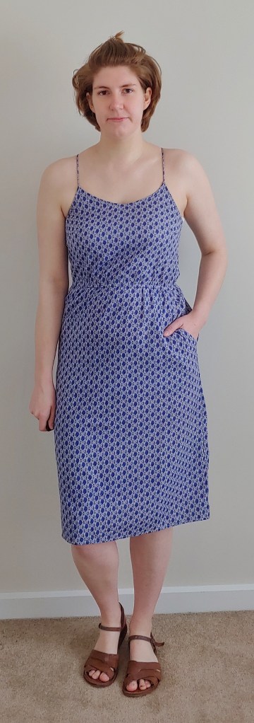 Full length photo of Helen wearing a blue dress with white netting-print, with pockets.