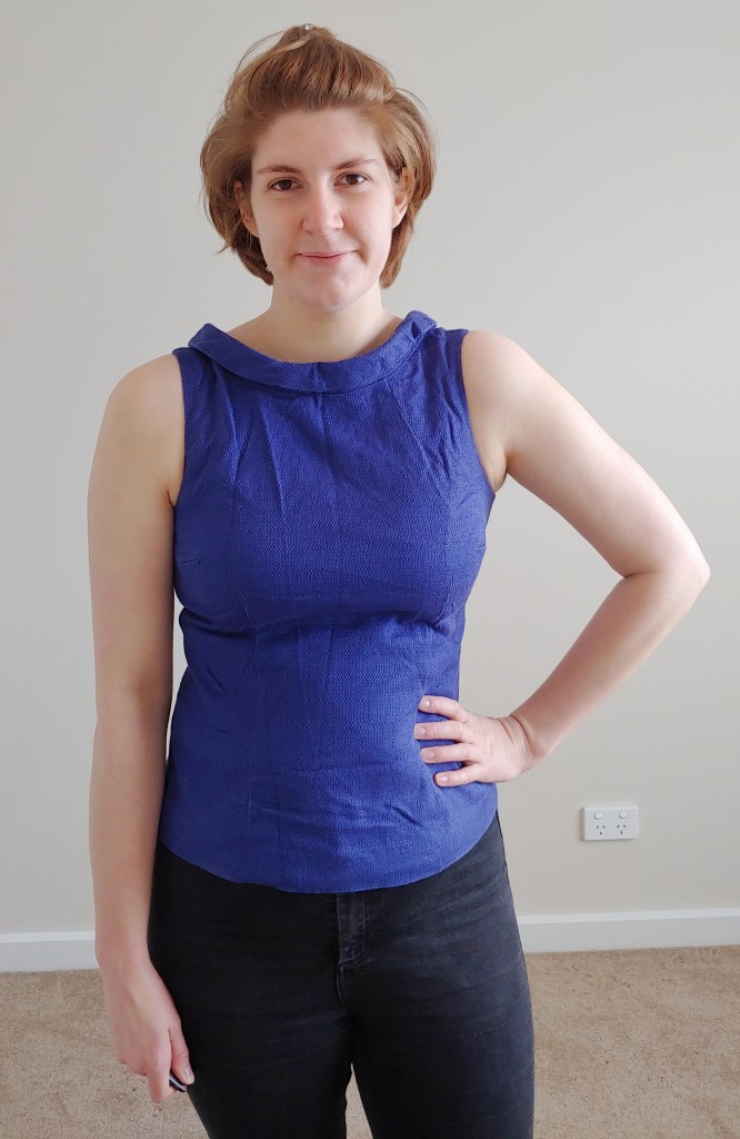 Helen wearing a rich blue sleeveless shell top with a folded wide collar.