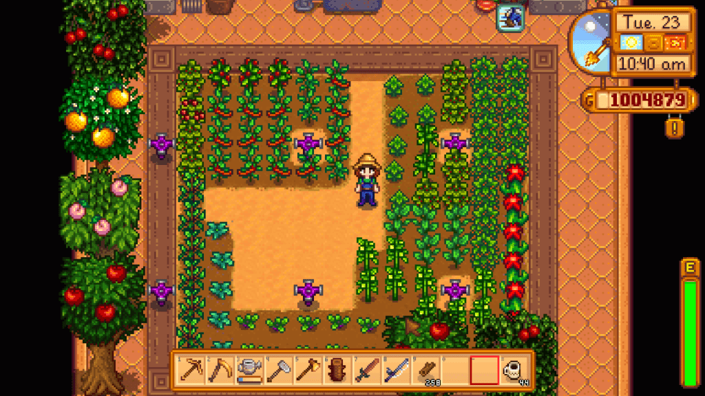 Screenshot showing a greenhouse in Stardew Valley complete with trees, sprinklers, and lots of different types of plant.