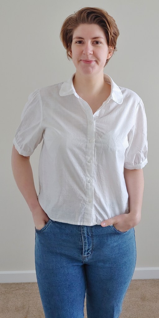 Helen wearing a white shirt with short sleeves and a Peter Pan collar, with blue jeans.