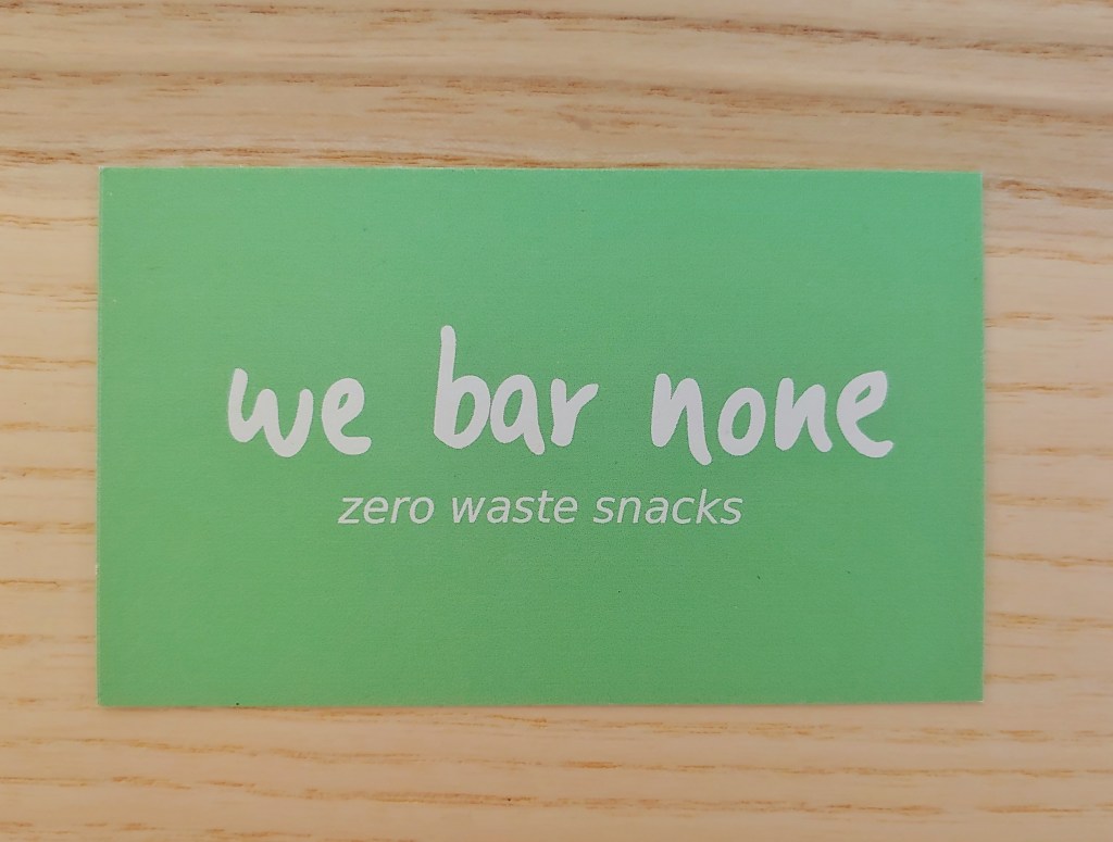 Business card with 'we bar none' in a hand written style font, with 'zero waste snacks' underneath in a arial type font, both in white on a minty green background.