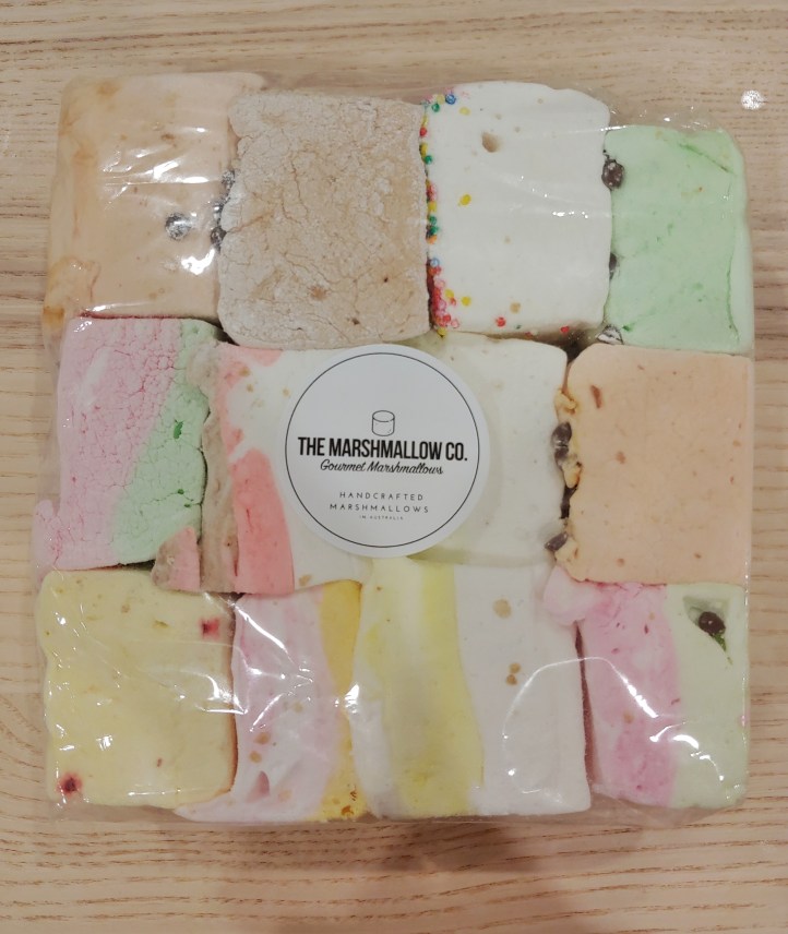 Close up of a flat bag of large, colourful chunks of marshmallows cut into large squares.