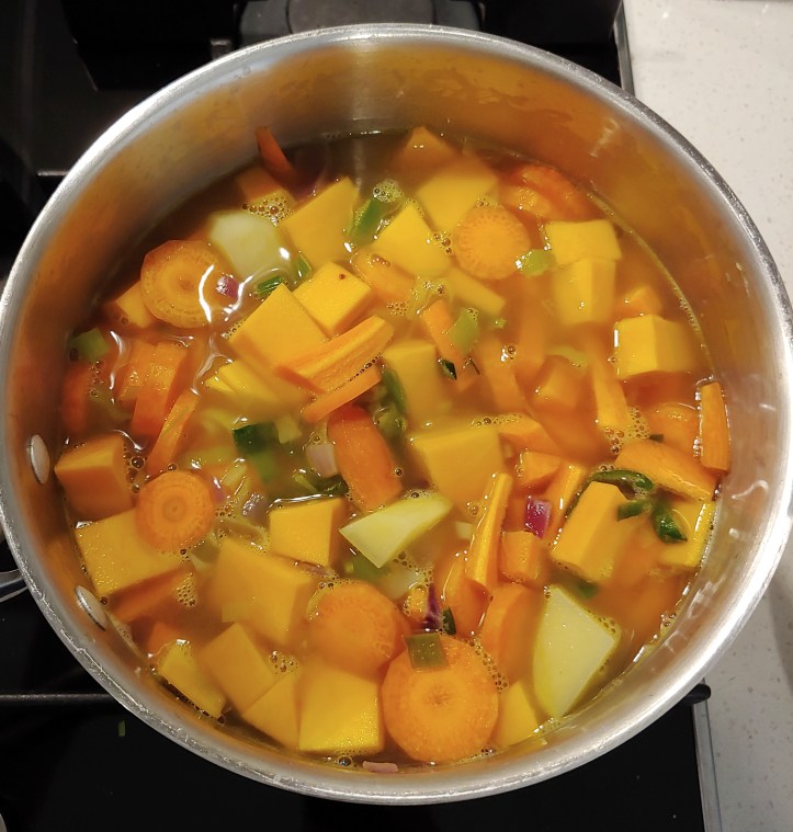 The raw vegetables added to the pan with the stock.