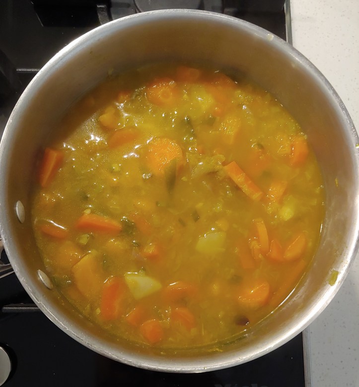 Cooked vegetables in the pan, looking soft and tender.