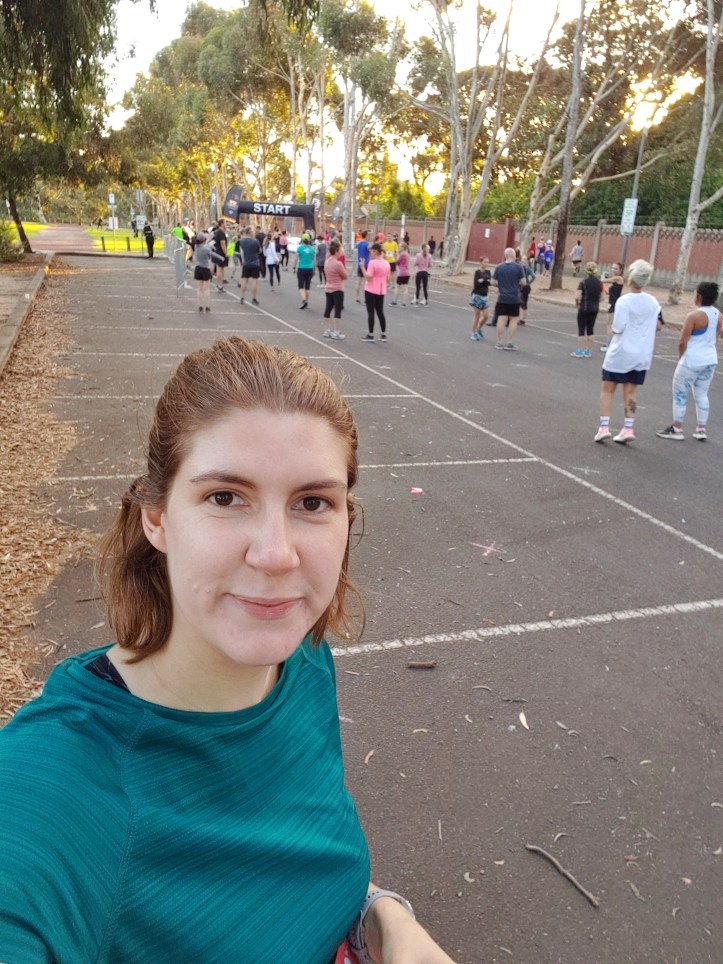Selfie photo of Helen at the start line, with other runners and tall gum trees in the background.