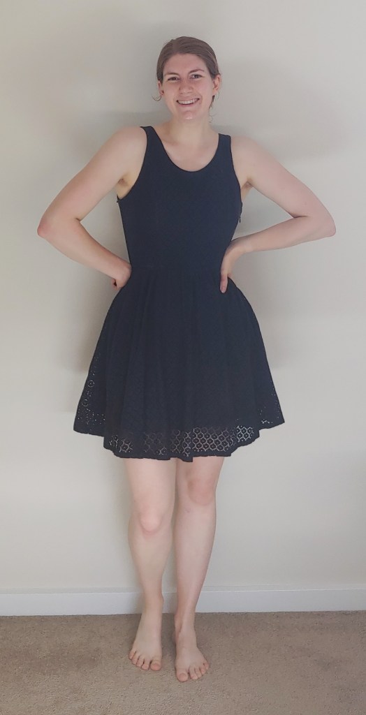 Full length photo of Helen wearing a navy-blue, sleeveless lacy mini-dress.