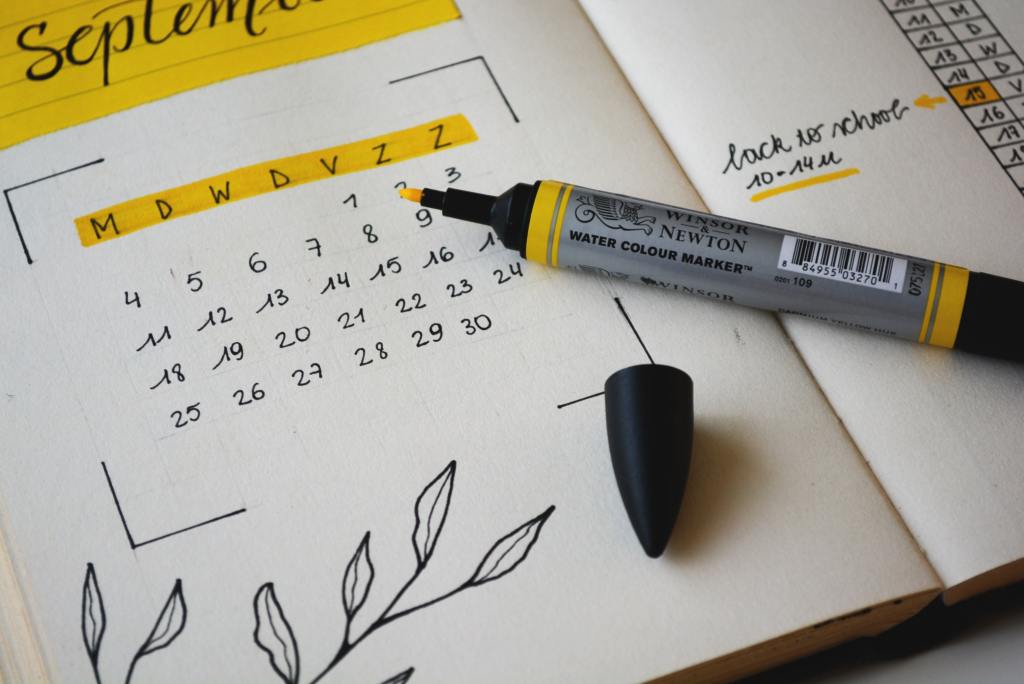 Close-up of a planning journal with a month calendar and a yellow highlighter