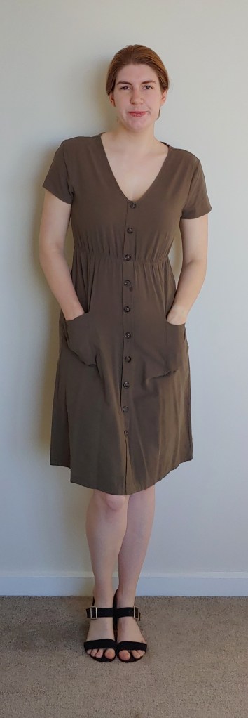 Helen wearing a khaki green knee-length v-neck dress with short sleeves and buttons down the front, with black block-heeled sandals.