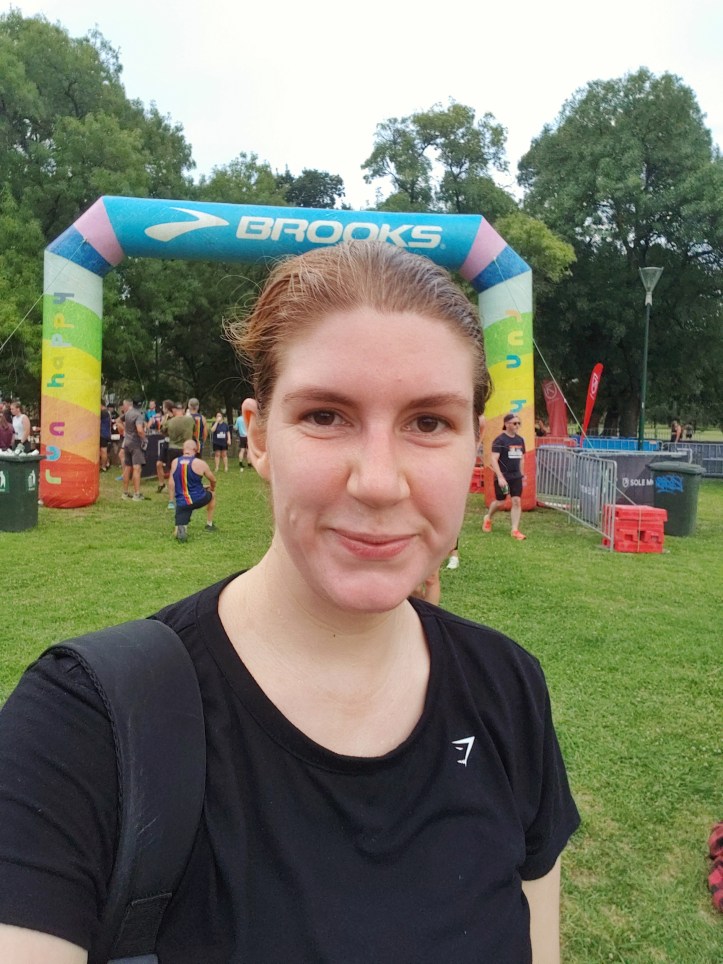 Photo of Helen in sports gear in front of a running race finish line.