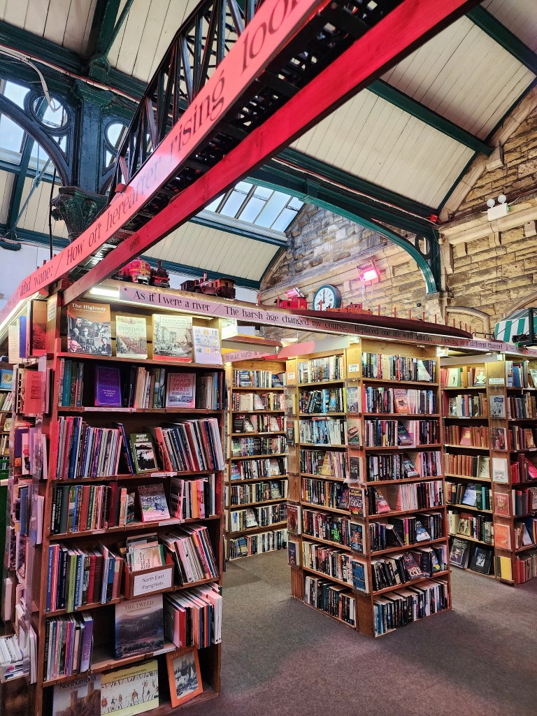 Square bookshelves under the cast iron joists of the original station, with a small model railway running along the top.