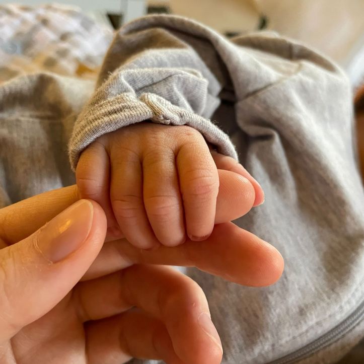 Close-up of a baby's hand holding Helen's finger.