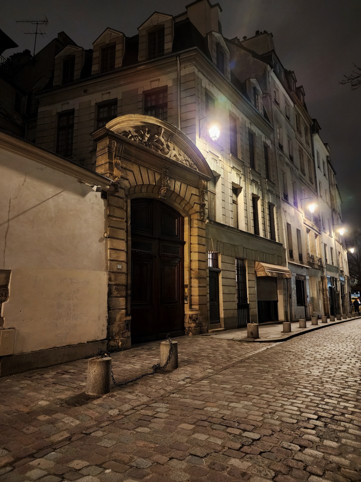 A large, ornately decorated gateway next to a four-storey townhouse.