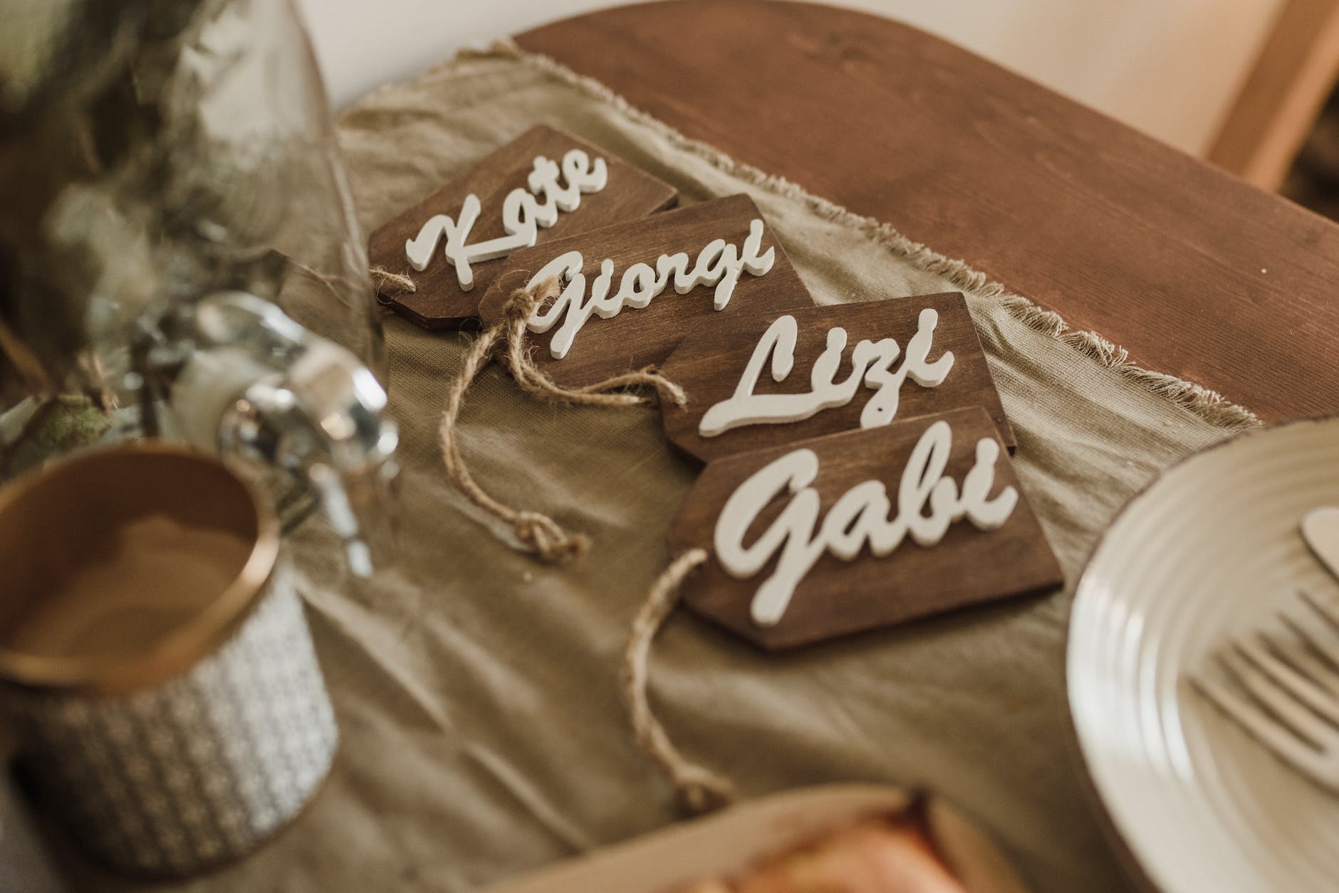 Four wooden name tags on a wooden table, reading 'Kate', 'Giorgi', 'Lizi' and 'Gabi'
